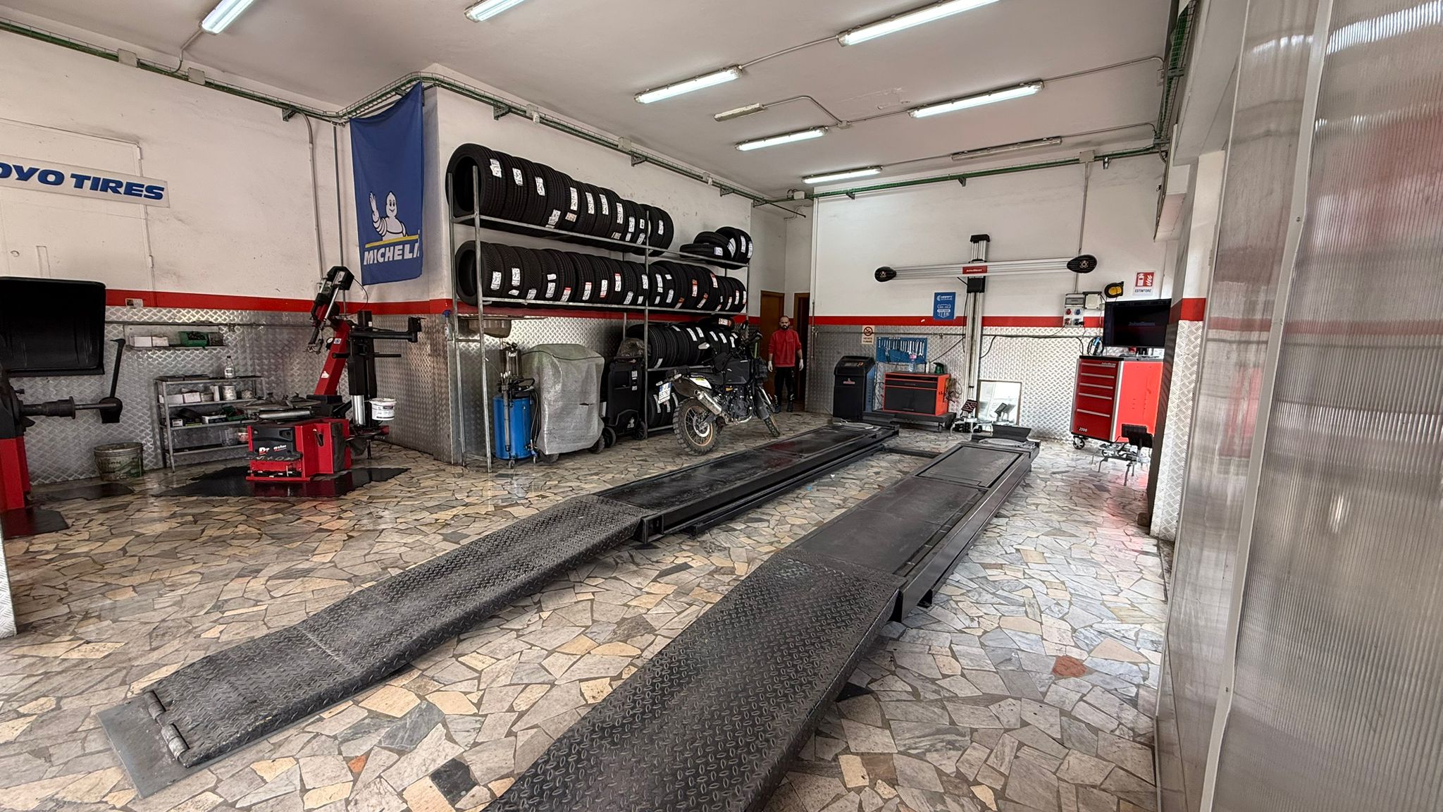 Area tecnica con macchine per lavorazioni pneumatici e strumenti di officina