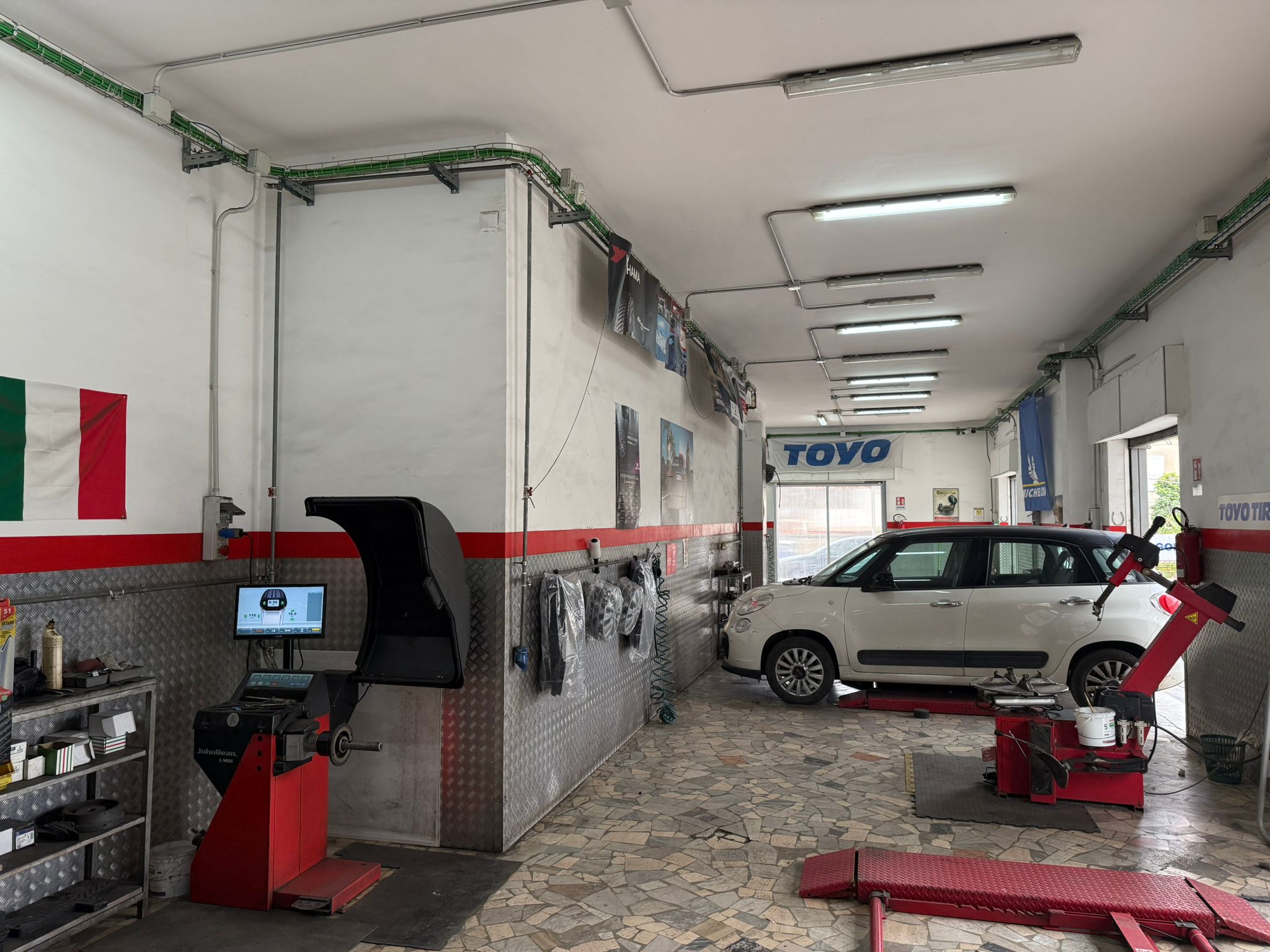 Vista interna dell'officina con auto in lavorazione e postazioni tecniche