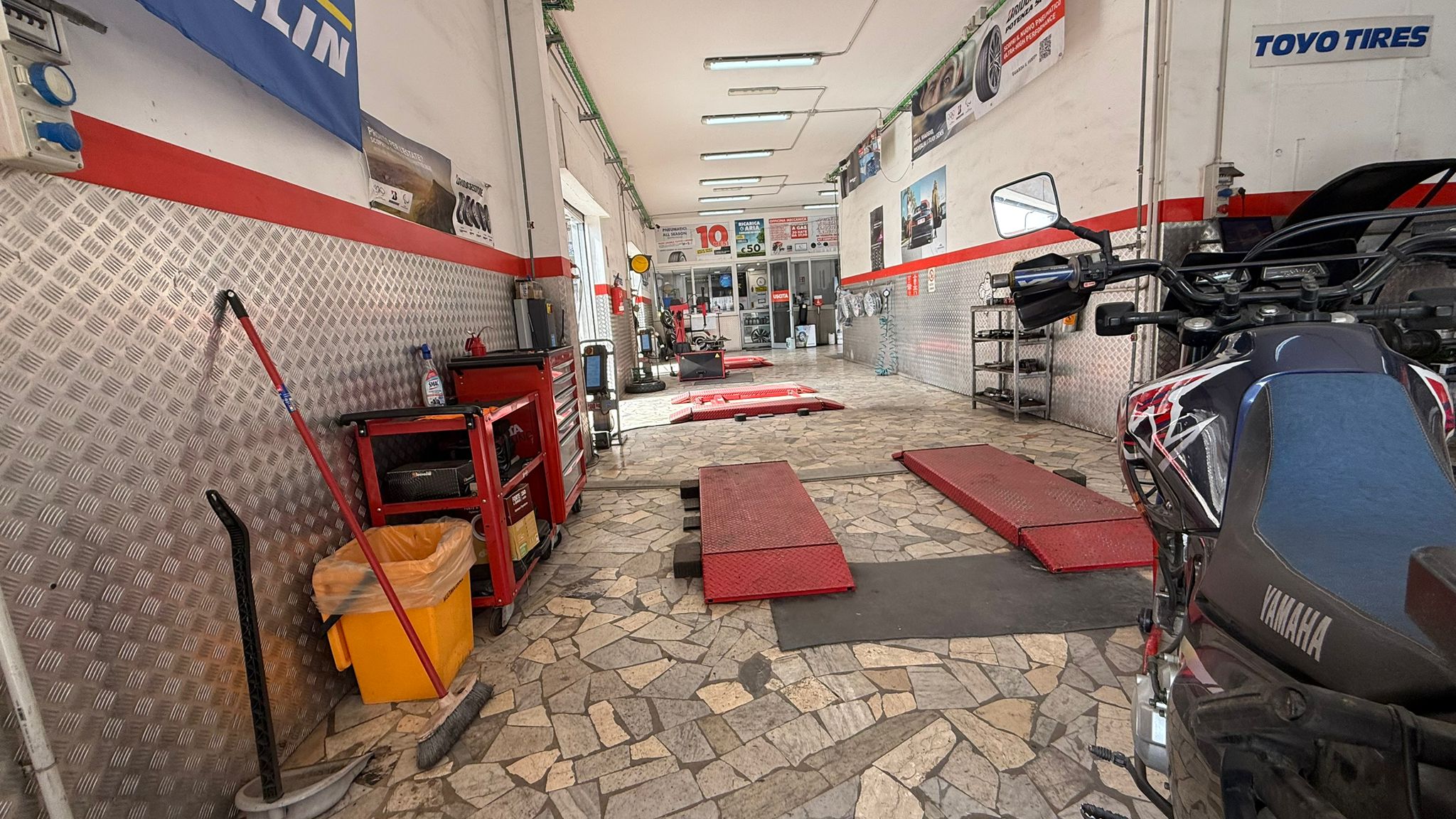 Spazio operativo dell'officina con area moto e corsie di lavorazione