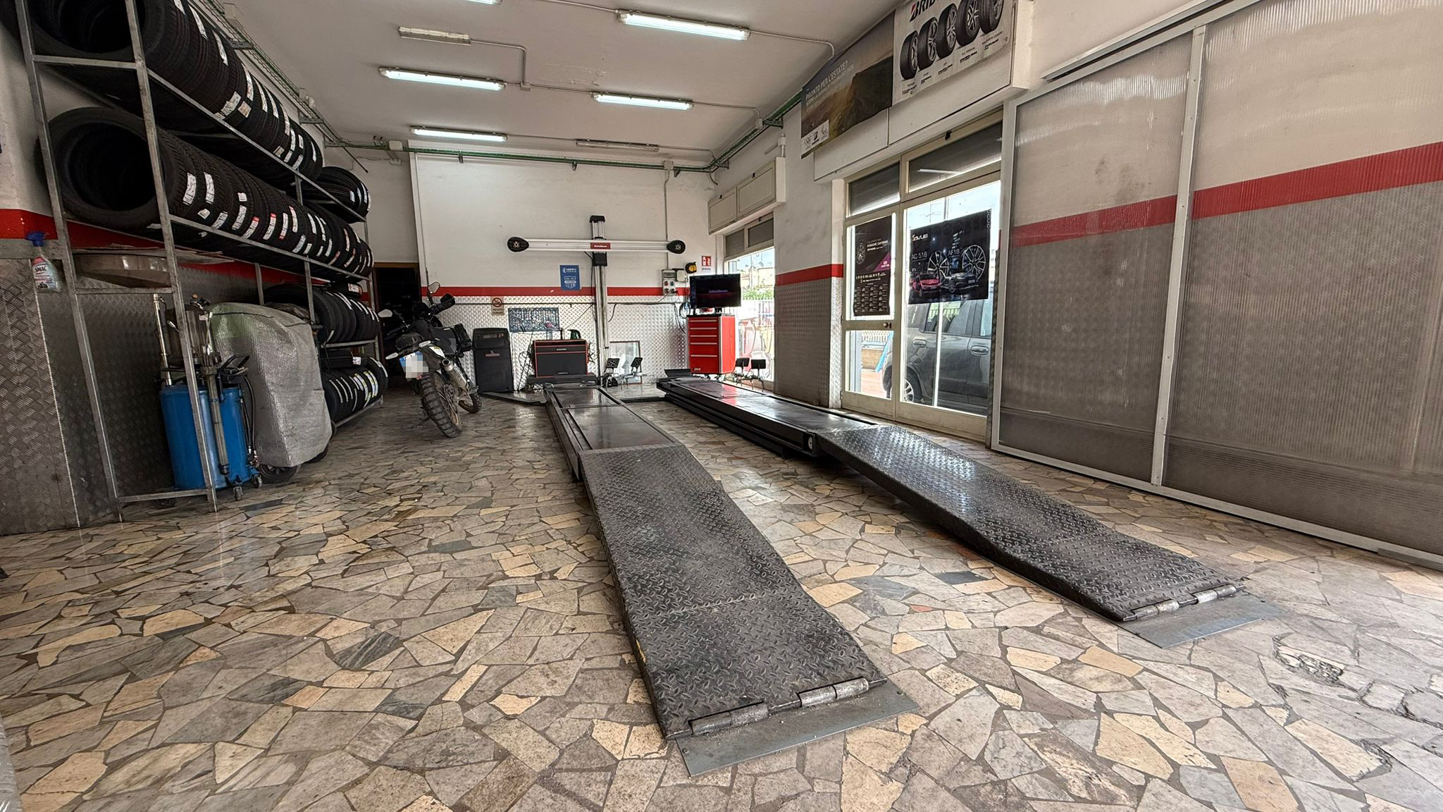 Vista ampia dell'officina Aversa Gomme con ponti, scaffali pneumatici e area moto