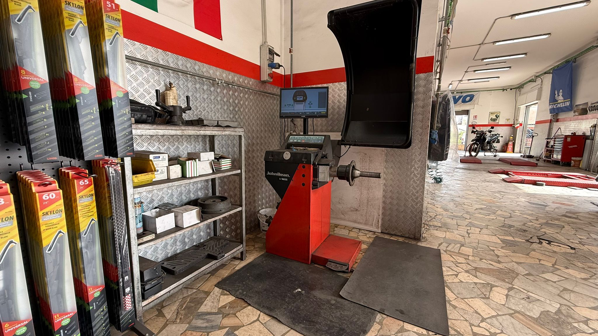 Area clienti con banco rosso, vetrine e postazione di accoglienza